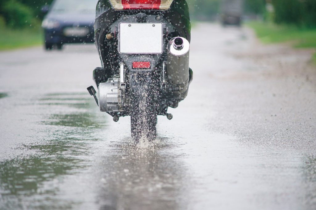 A view of a motorcycle in the rain from behind